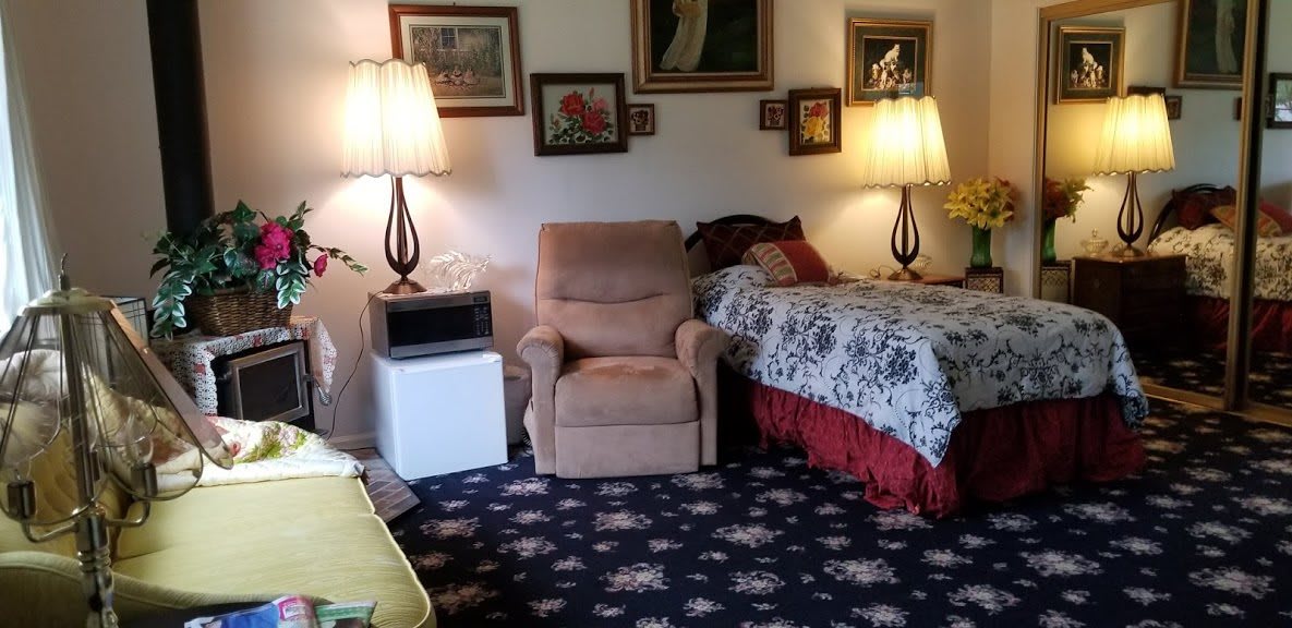 Cozy living space with an armchair, two lamps, and a bed surrounded by wall art.