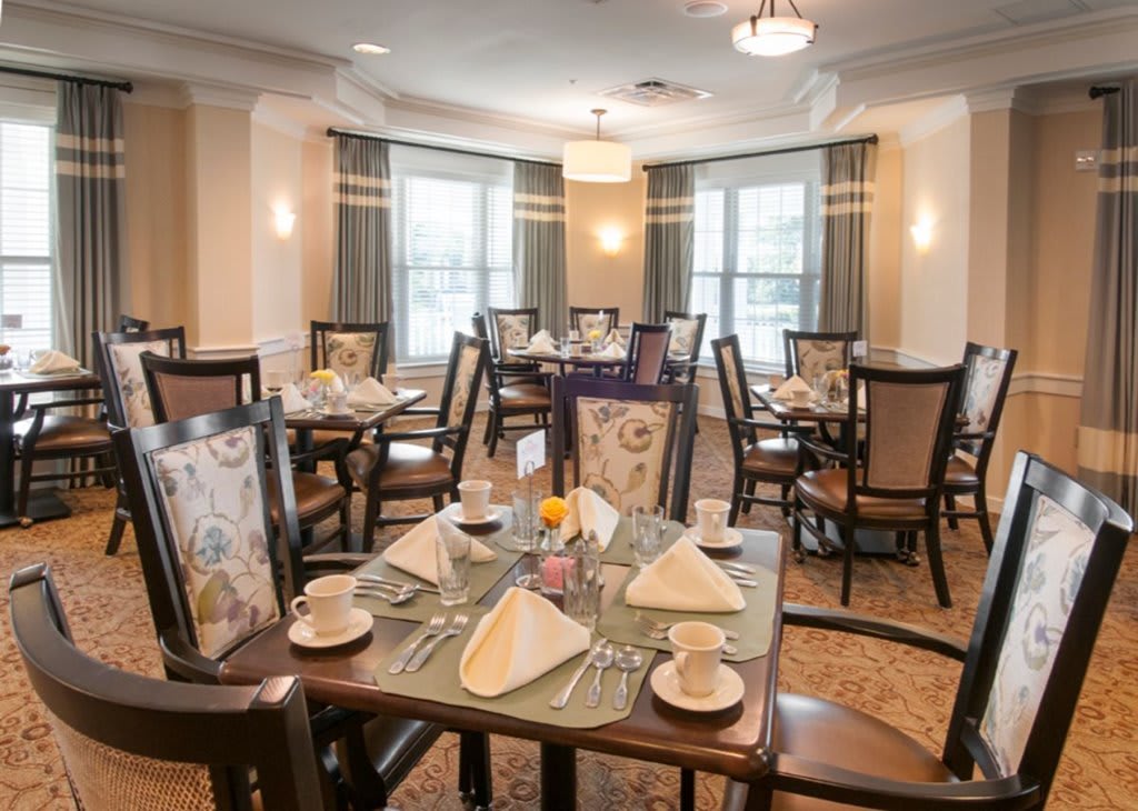 An elegantly set dining room with neatly arranged tables and chairs, ready for guests.