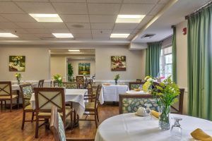 A well-decorated dining room with neatly arranged tables and chairs, adorned with flowers.