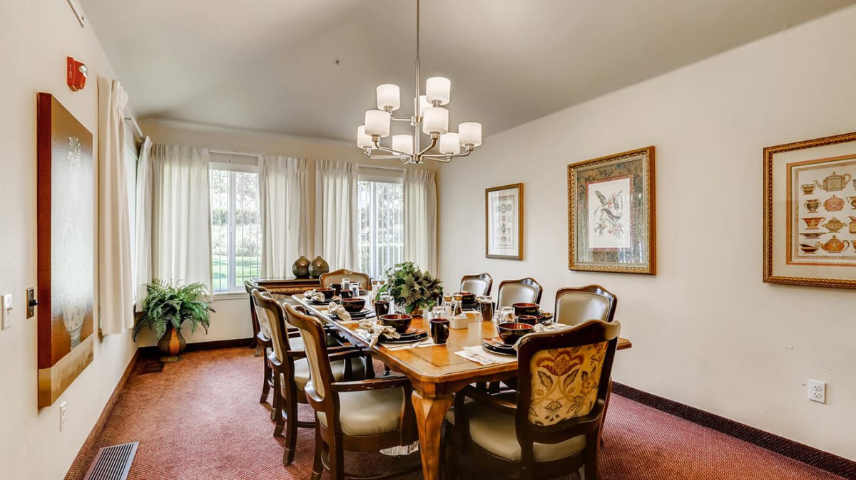 A well-decorated dining room with a wooden table, elegant chairs, and a chandelier.
