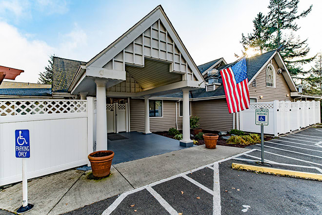 An entrance to a building with an American flag and adjacent parking spaces.