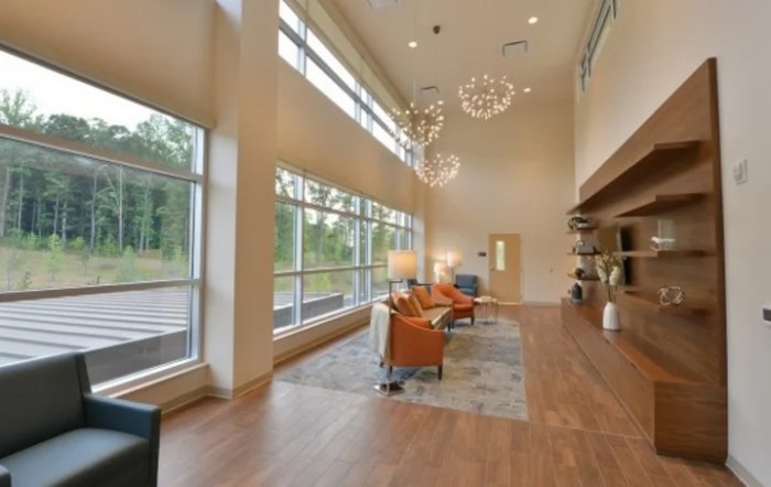 A modern and spacious lobby area featuring large windows, elegant chandeliers, and comfortable seating.