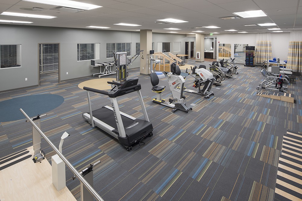 A well-equipped gym with treadmills, stationary bikes, and other exercise equipment on a carpeted floor.
