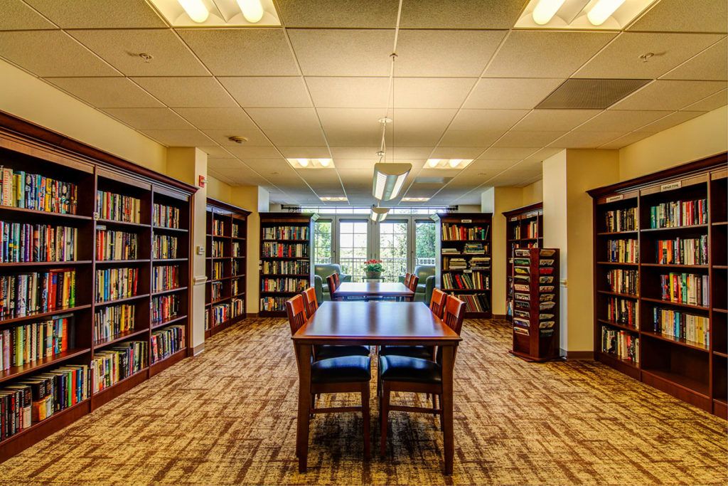 A quiet library room with bookshelves and a central table for reading.