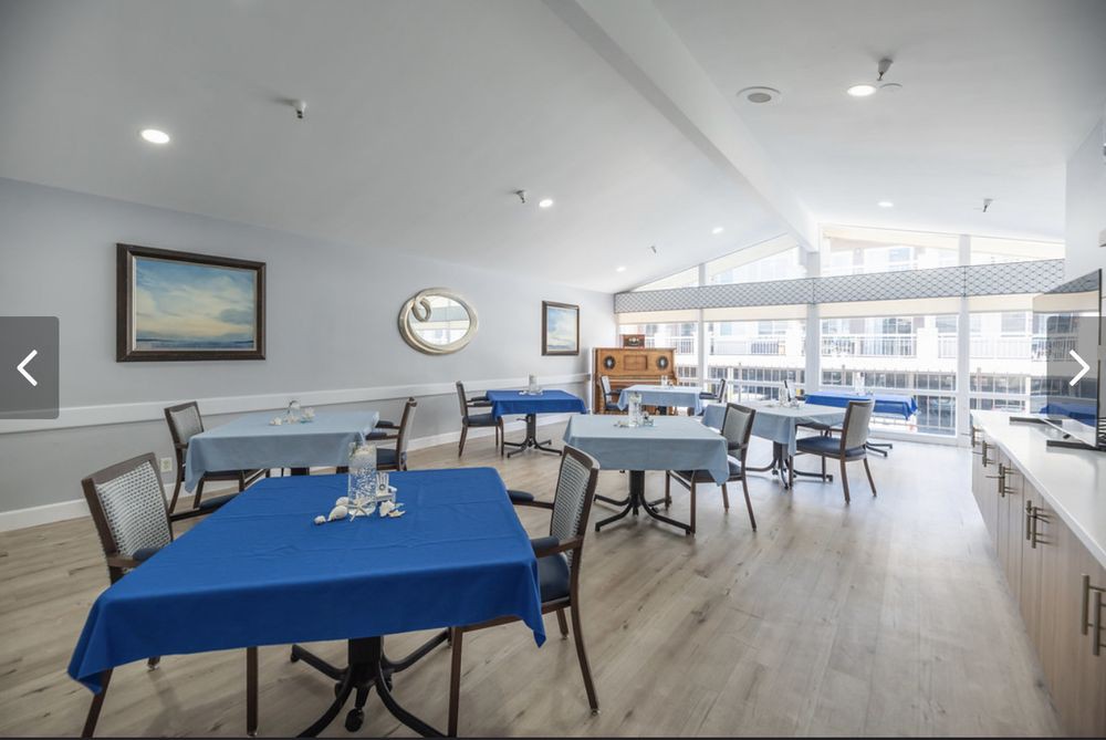 A bright dining area with blue tablecloths on the tables, surrounded by large windows.