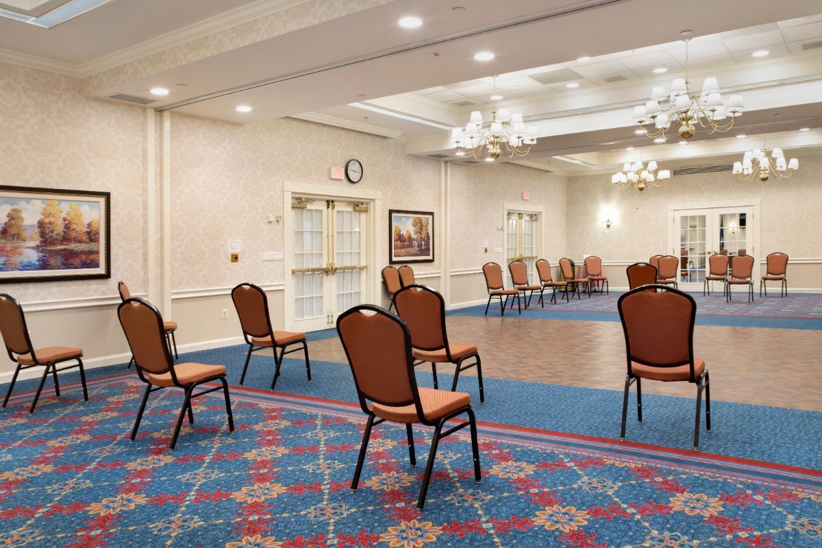 A spacious conference room with chairs arranged in a circle, featuring elegant lighting and a patterned carpet.