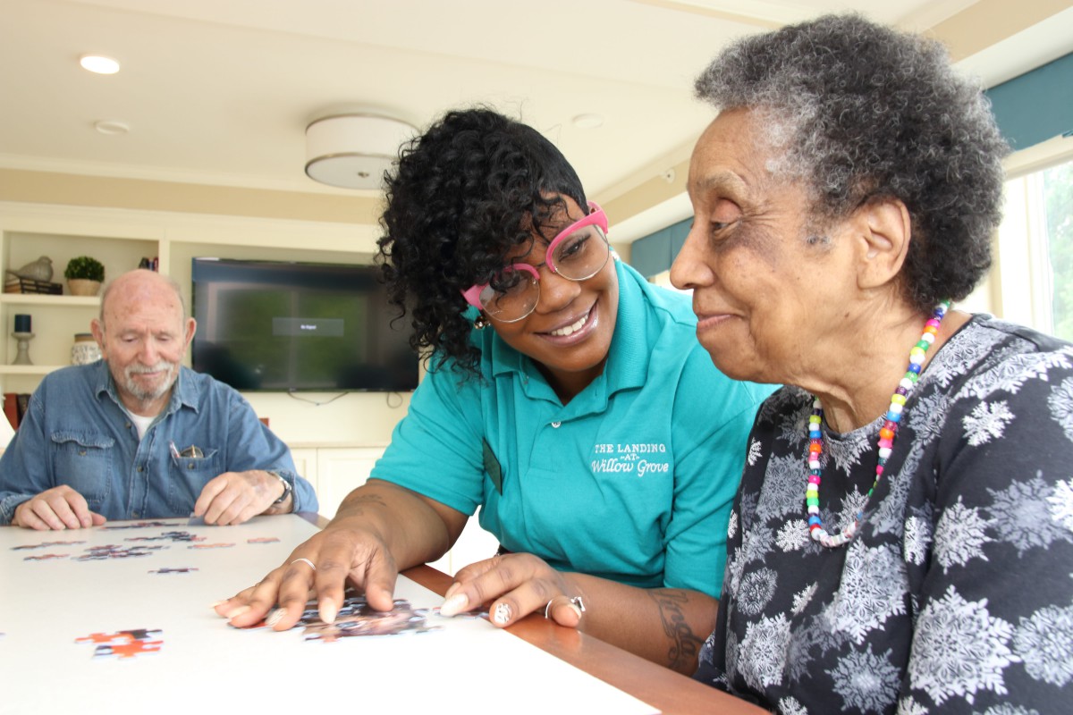 A caregiver smiling and interacting with an elderly woman.