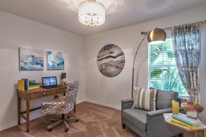 A cozy and stylish home office with art on the walls, a desk, and a comfortable chair.