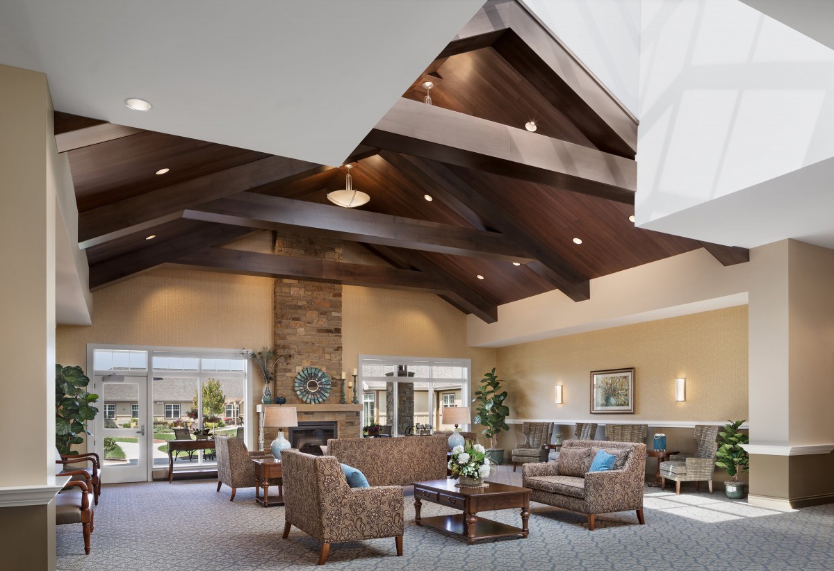 A spacious lobby featuring high wooden beam ceilings, comfortable seating, and large windows providing natural light.