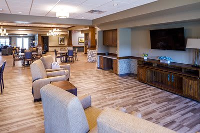 A modern lounge area featuring comfortable seating and a television, with wood flooring and elegant lighting.