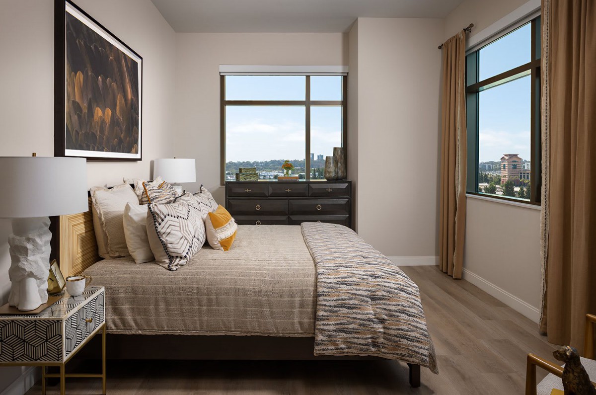 A modern bedroom with neutral tones and a scenic window view.