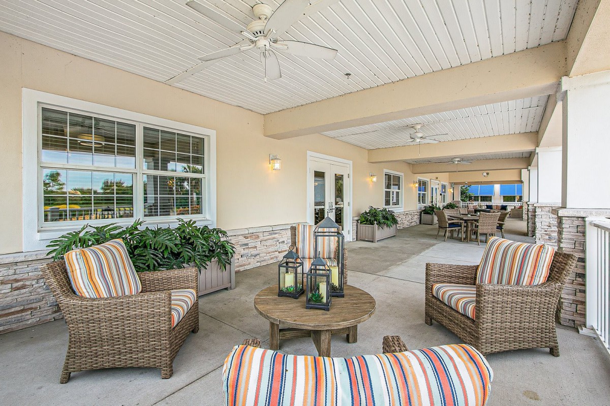 A cozy outdoor patio with wicker furniture, colorful cushions, and decorative lanterns.