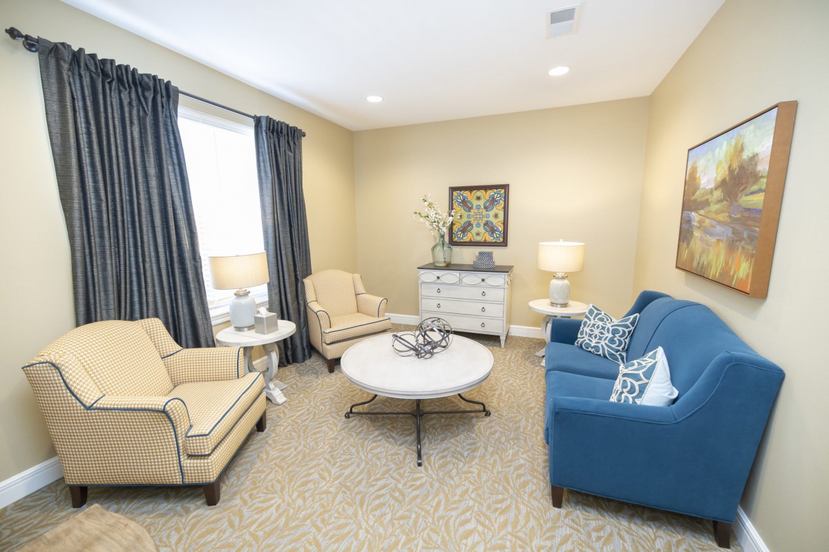 A cozy living room with a blue sofa, beige armchairs, and a round coffee table.