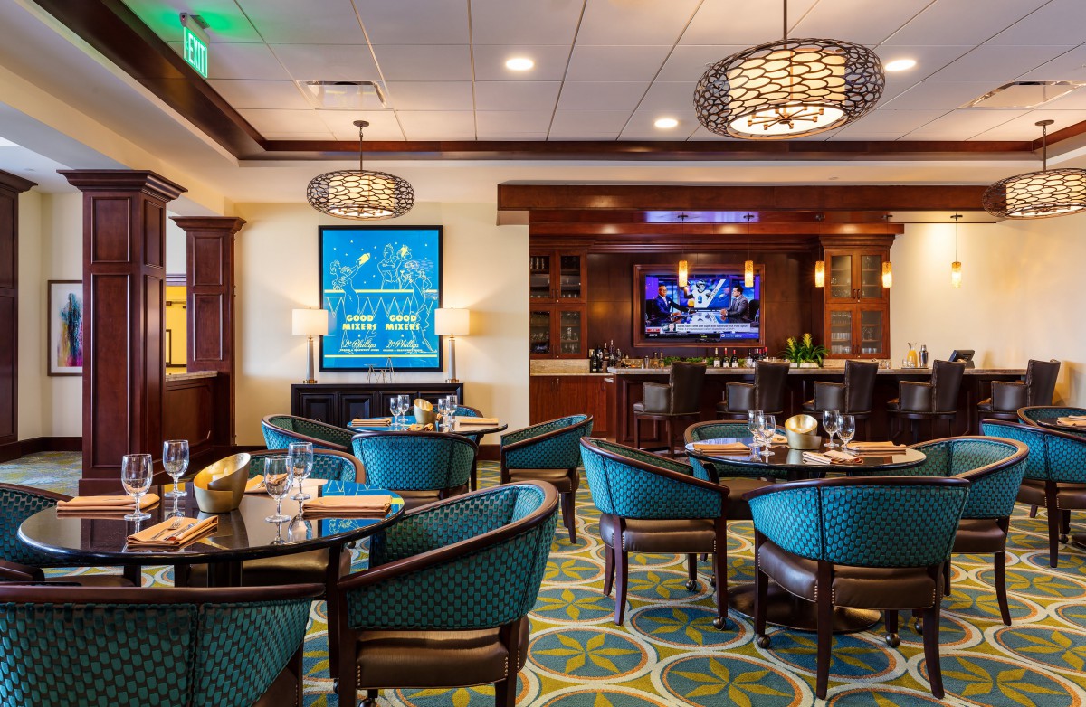 A cozy restaurant interior featuring a dining area with stylish chairs and tables, complemented by elegant lighting and decor.