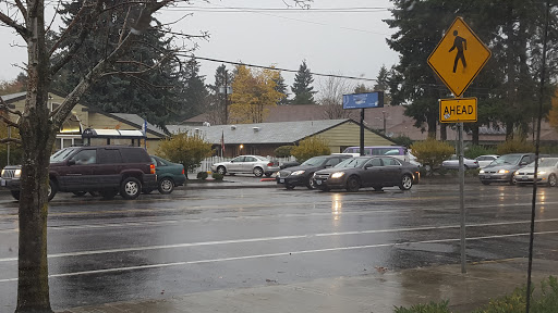 A rainy day scene showing cars at an intersection near residential houses.