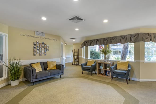A cozy living room featuring a sofa and chairs with decorative pillows, large windows, and tasteful decor.