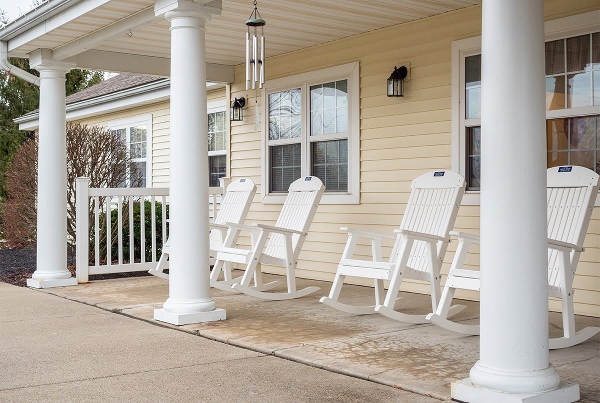 A cozy porch with white rocking chairs and sturdy columns.