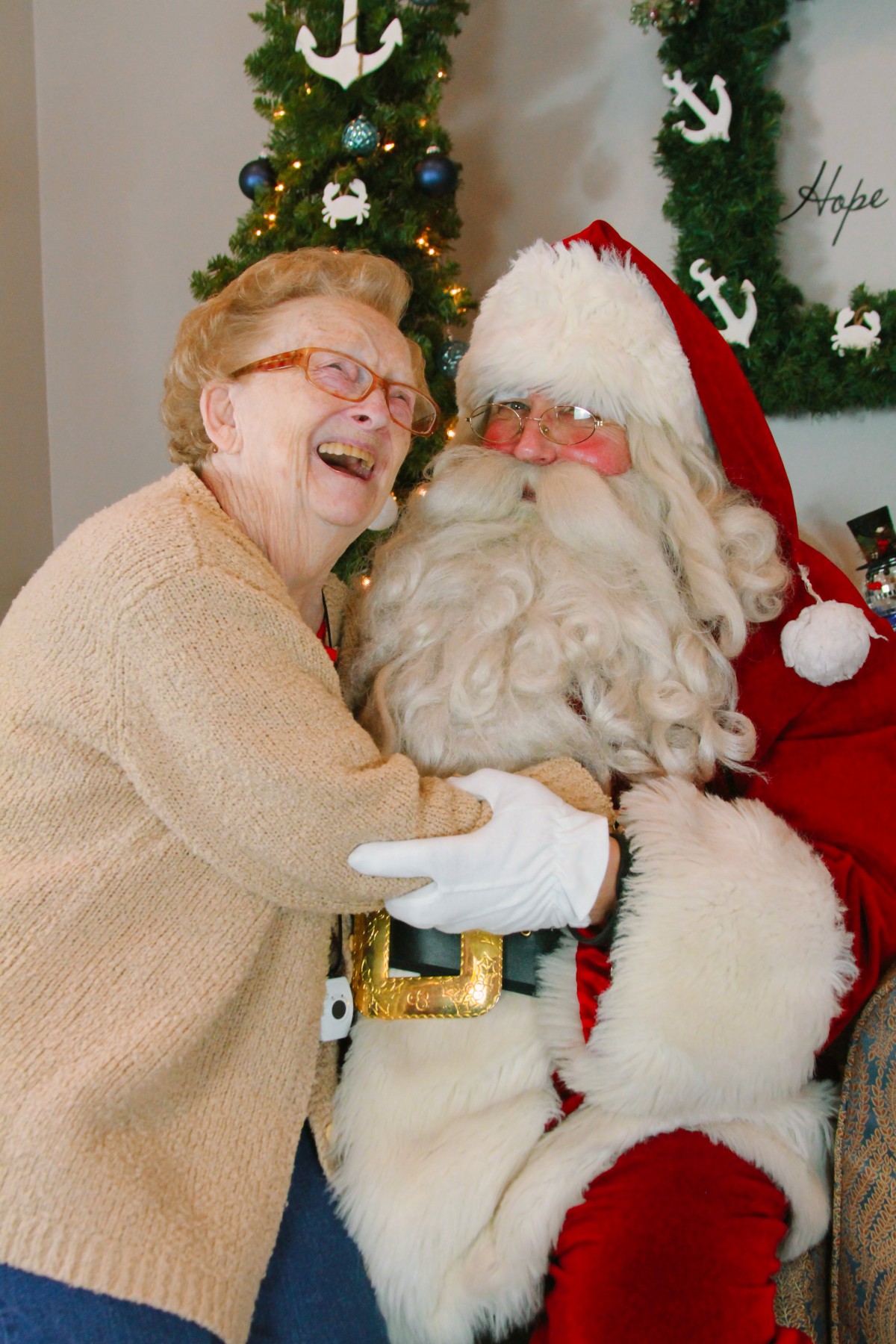 An elderly woman joyfully embraces Santa Claus during a festive holiday celebration.