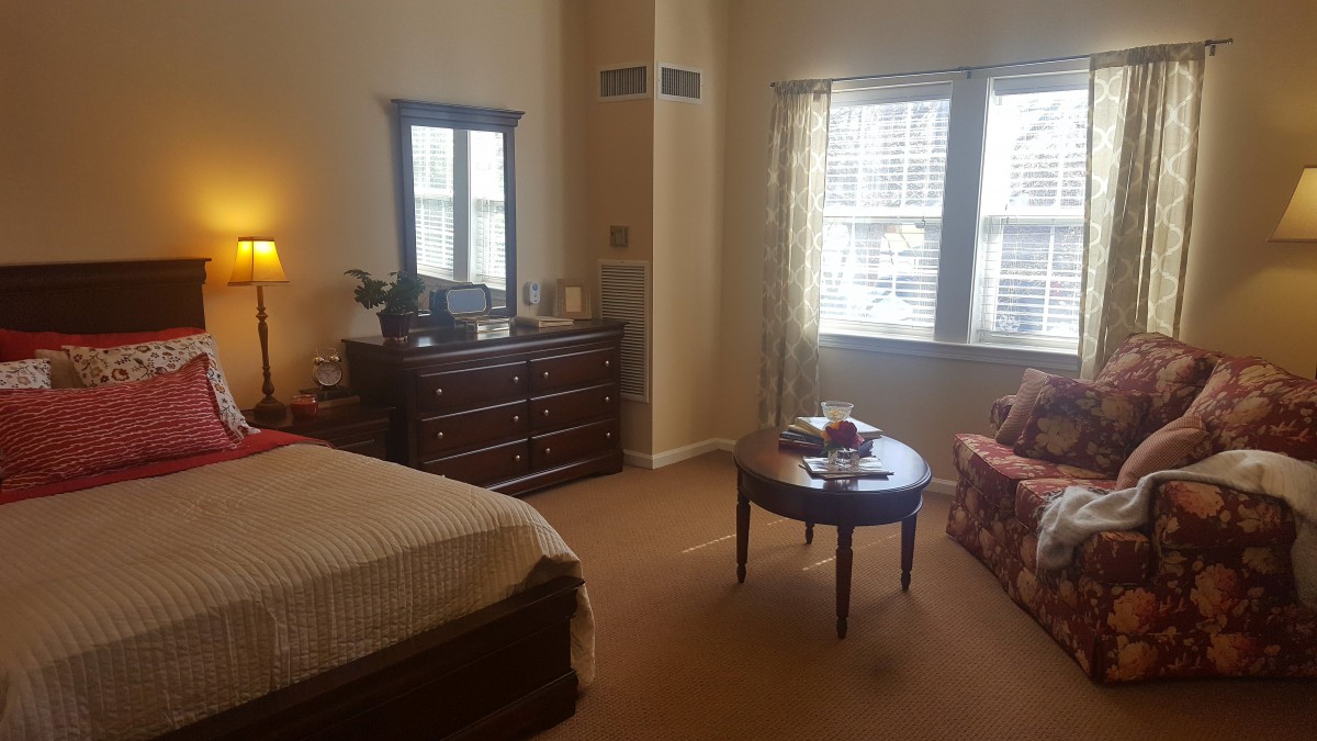 A cozy bedroom with a large dresser, mirror, and comfortable seating area.