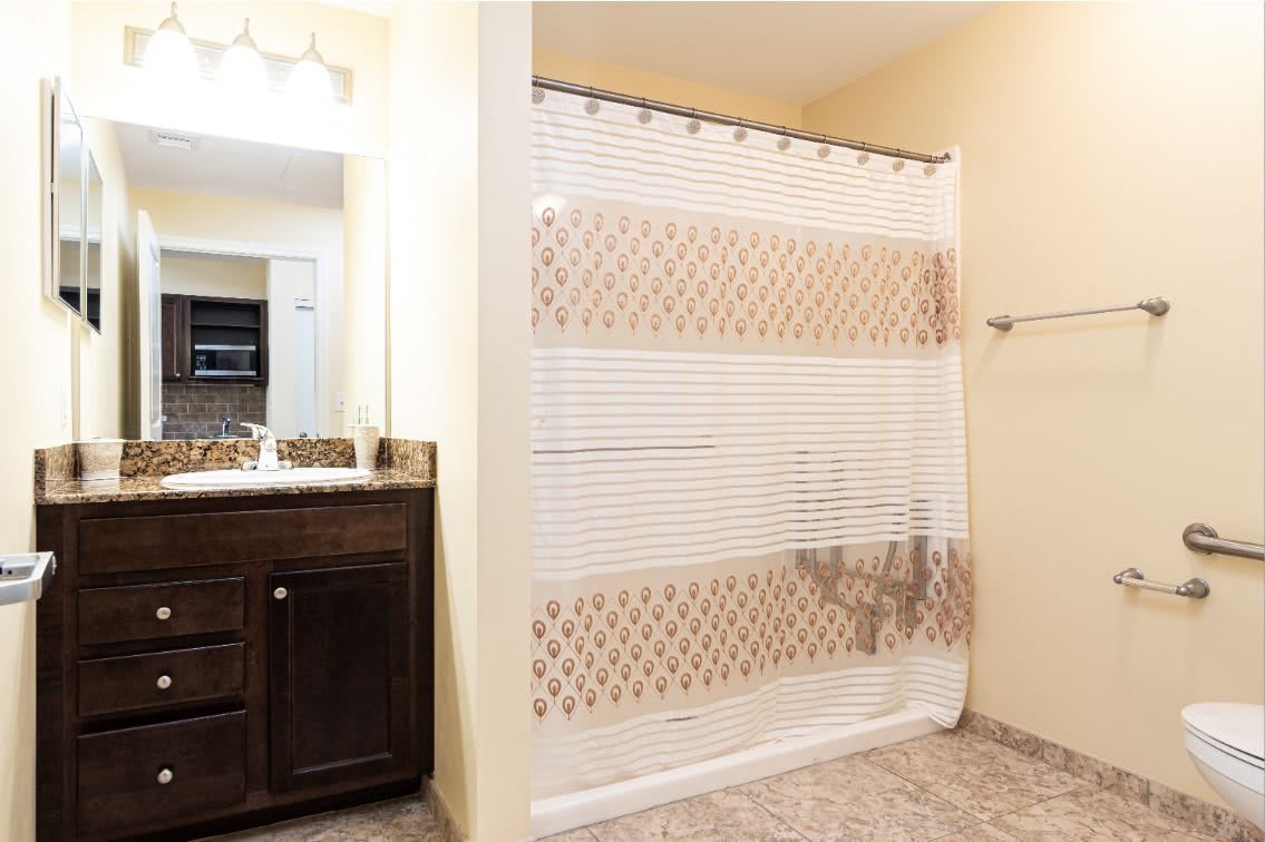 A modern bathroom with a patterned shower curtain and wooden vanity.