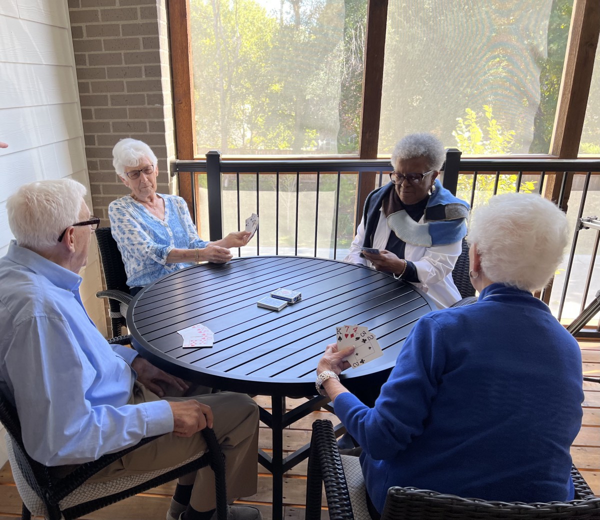 A group of seniors enjoying a card game on a sunny patio.