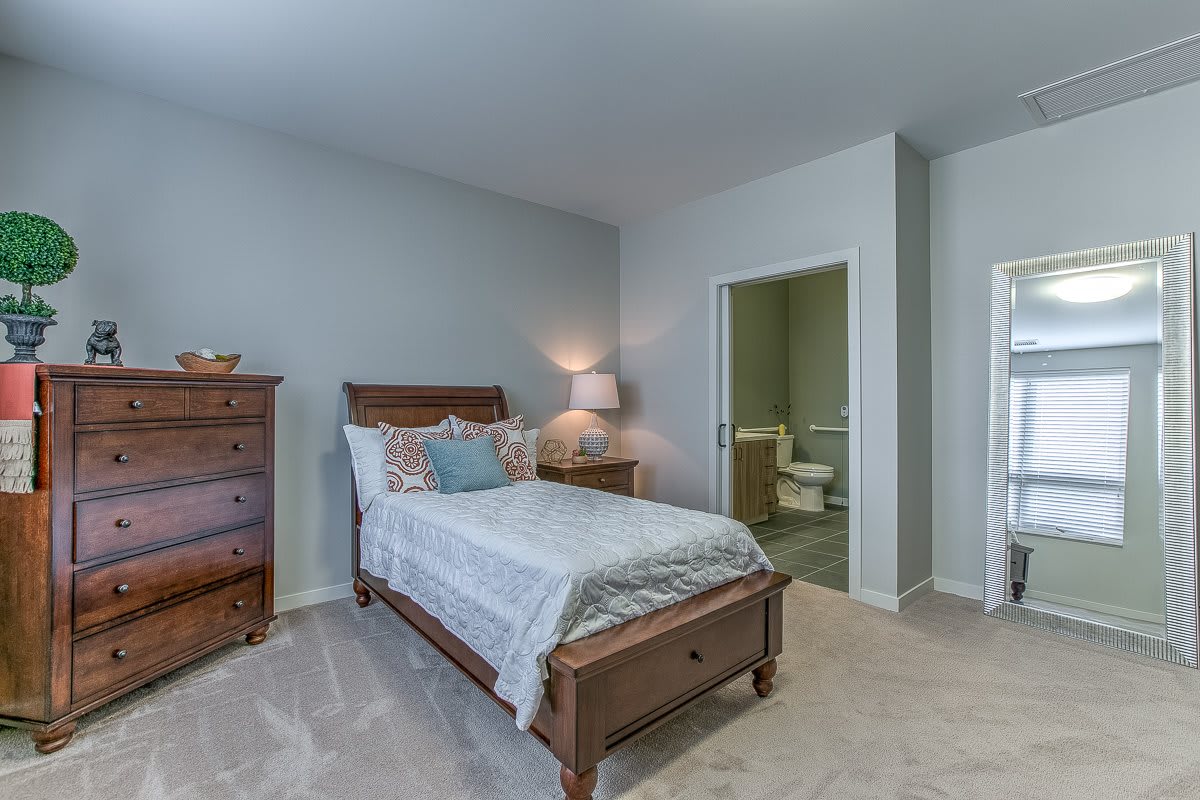 A cozy bedroom with a single bed, wooden furniture, and soft lighting.
