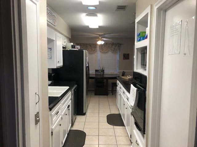A modern kitchen with white cabinets, black appliances, and tiled flooring.