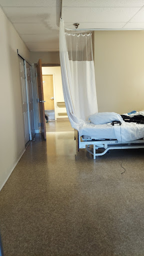 A view of a hospital patient room featuring an unmade bed and a privacy curtain.
