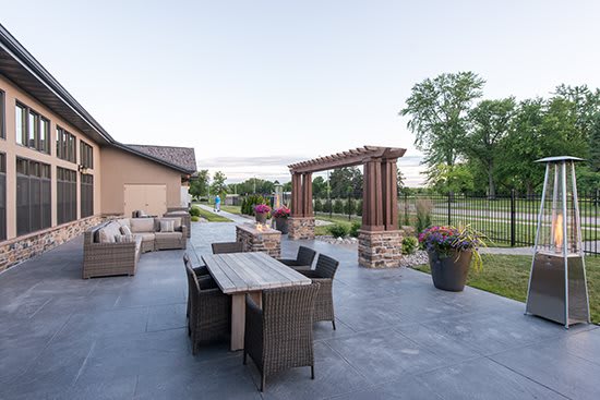 A spacious outdoor patio with comfortable seating and a dining area under a pergola, surrounded by a well-maintained garden.