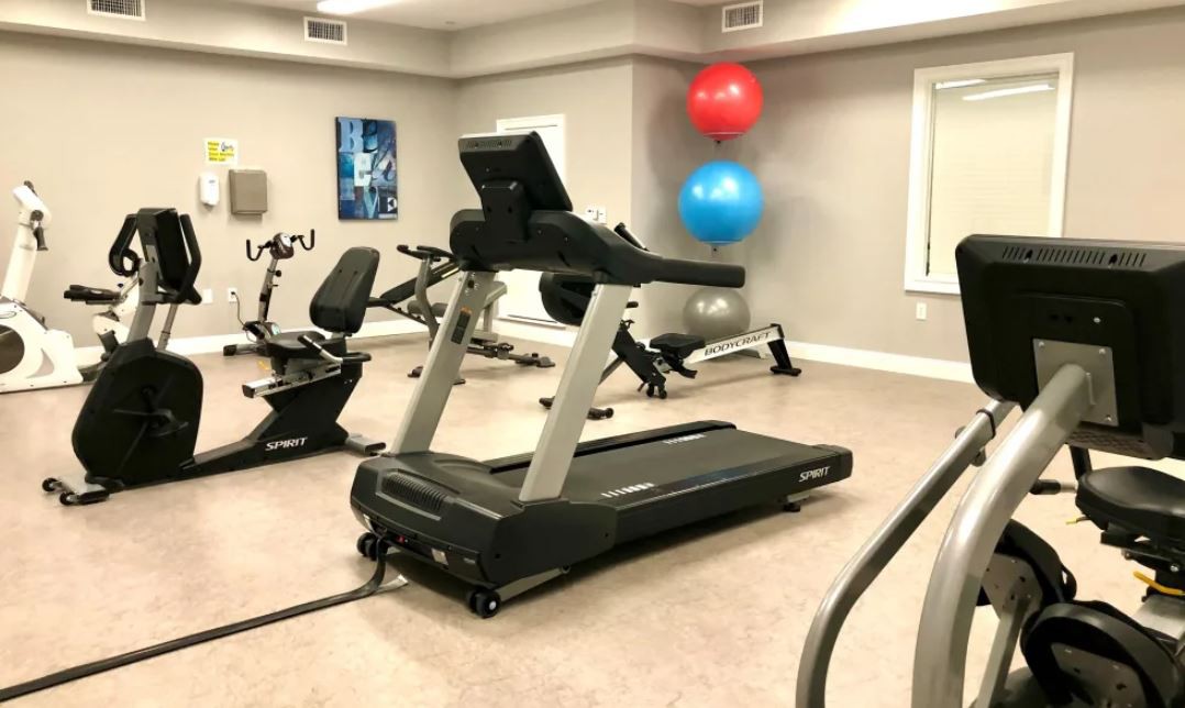 An empty gym with various exercise equipment, including a treadmill and exercise bikes.