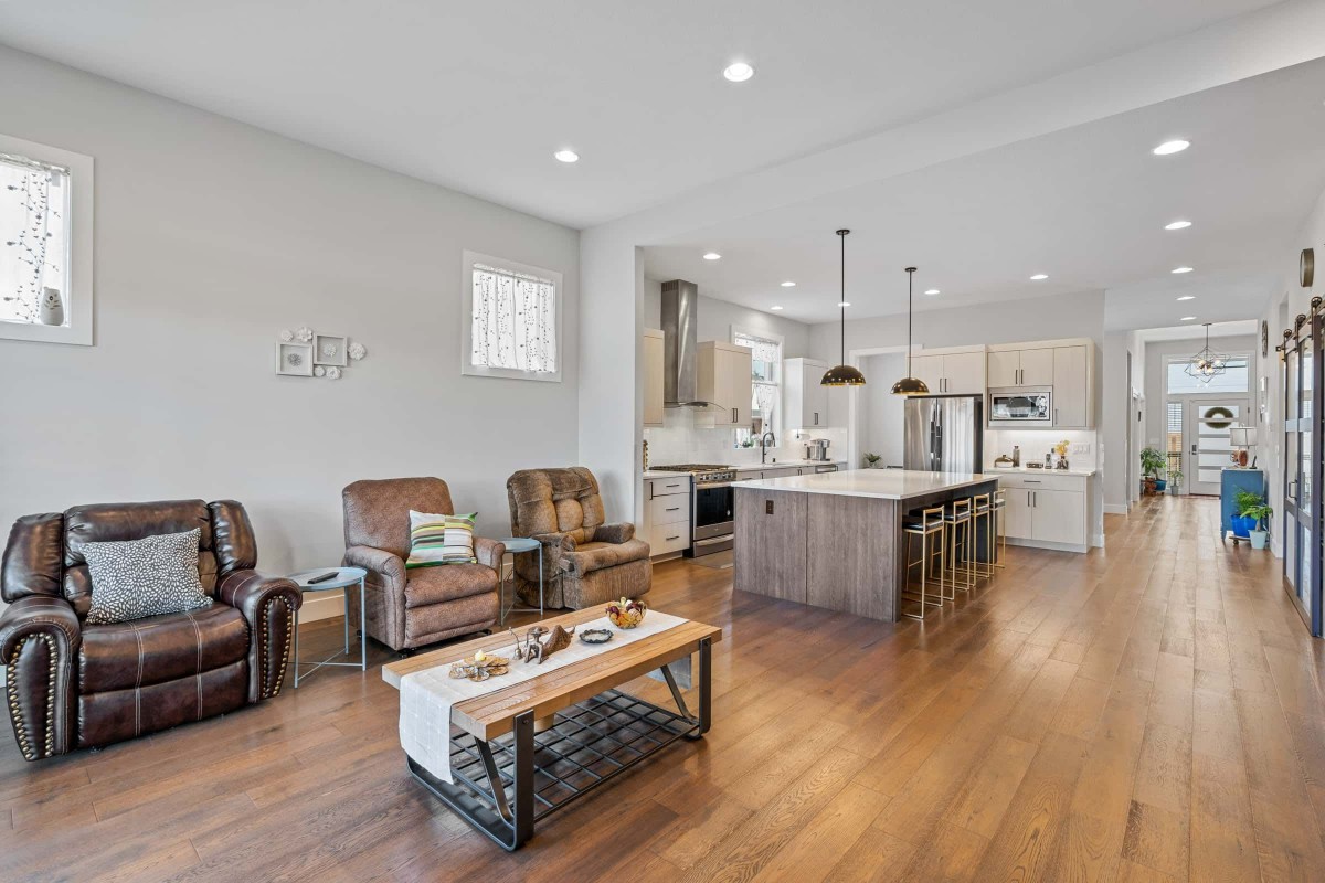 A modern open-concept living area with a spacious kitchen and hardwood floors.