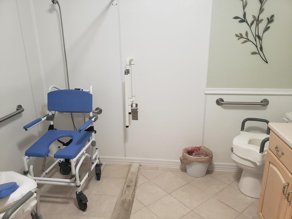 An accessible bathroom with a shower chair and grab bars for support.