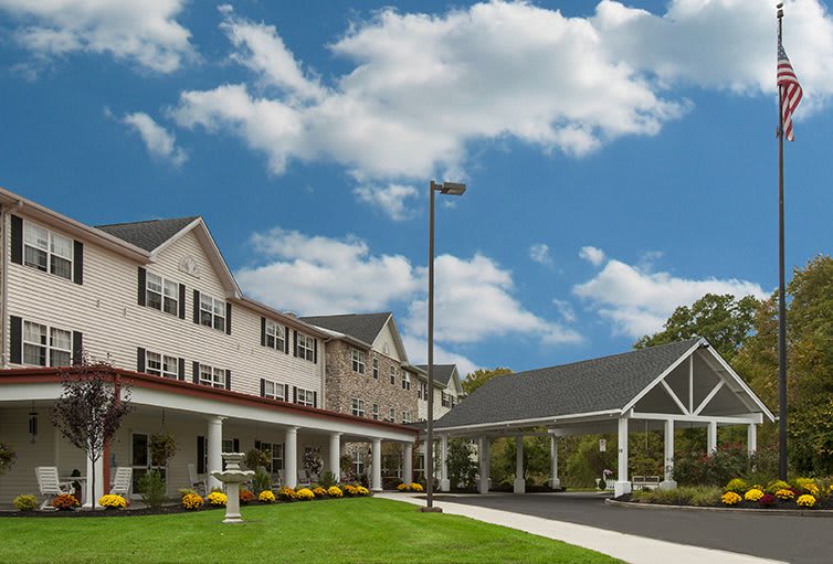 A spacious building with a well-maintained lawn under a bright blue sky with fluffy clouds.