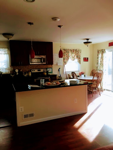 A cozy kitchen with wooden cabinets, dining table, and bright sunlight streaming in.
