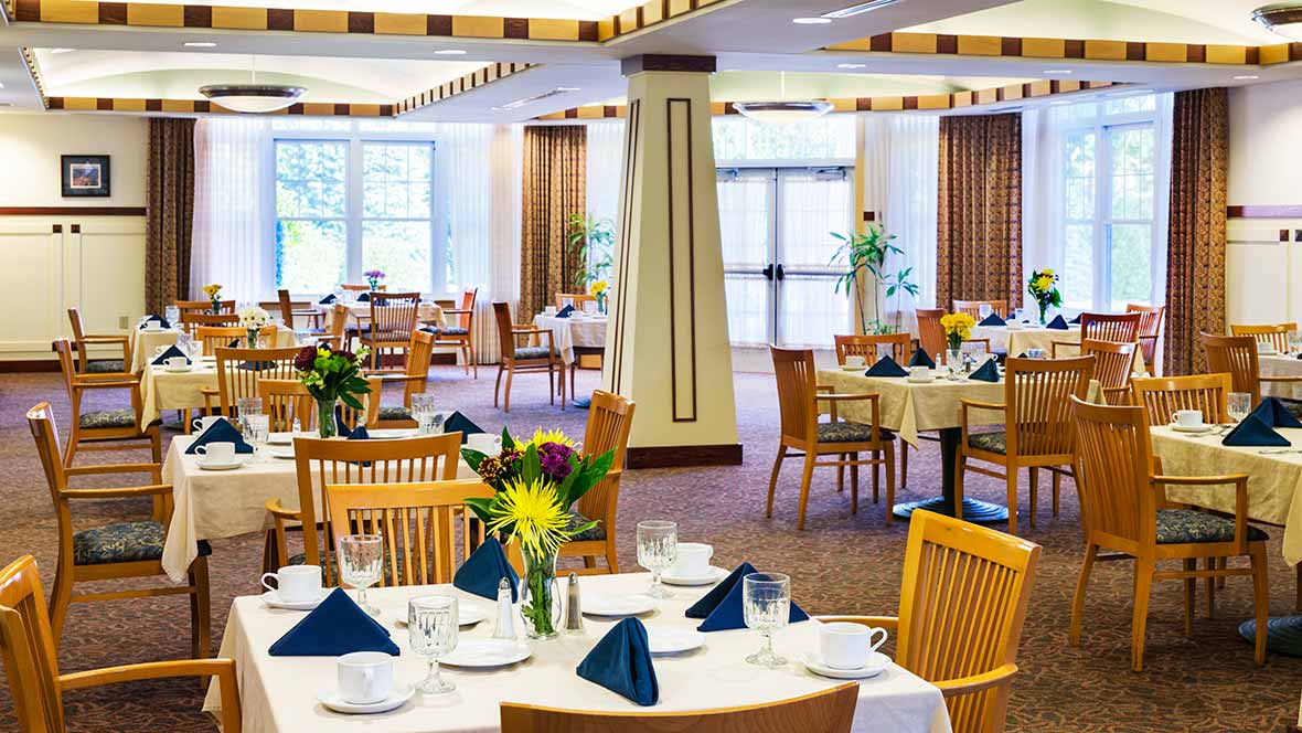 A well-arranged restaurant dining area with neatly set tables and decorative flowers.