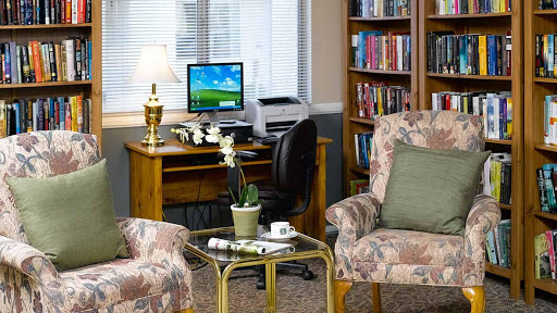A cozy office space featuring a computer desk, comfortable seating, and a well-stocked bookshelf.