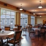 A spacious dining area with neatly arranged tables and chairs, featuring large windows allowing natural light to illuminate the space.