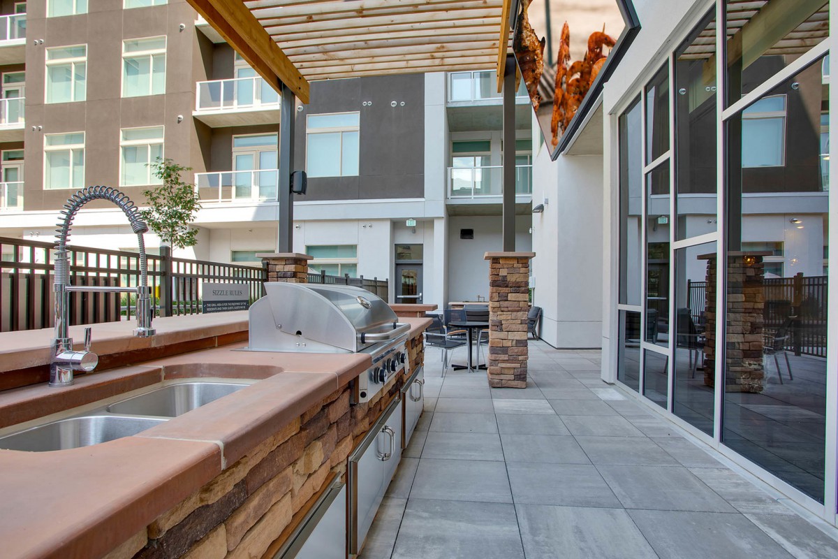 Modern outdoor patio with barbecue grill and seating area in an apartment complex.