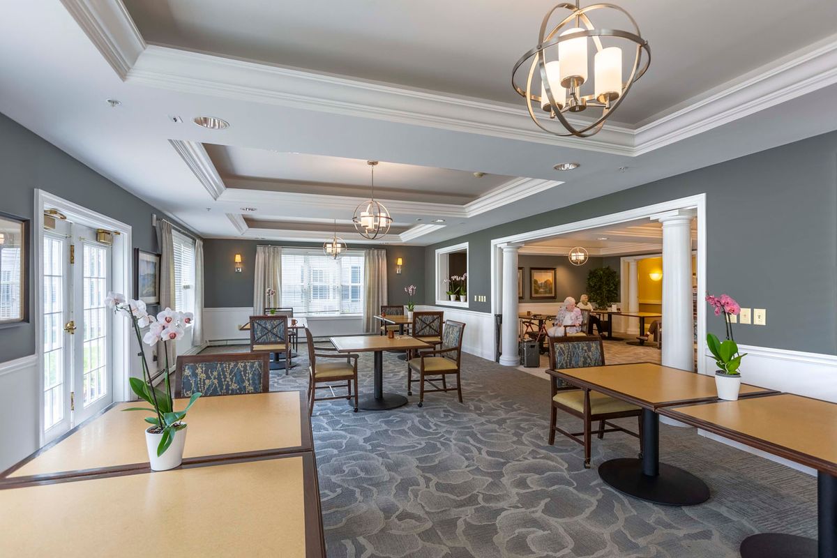 An elegantly designed dining area featuring tables, chairs, chandeliers, and natural lighting.