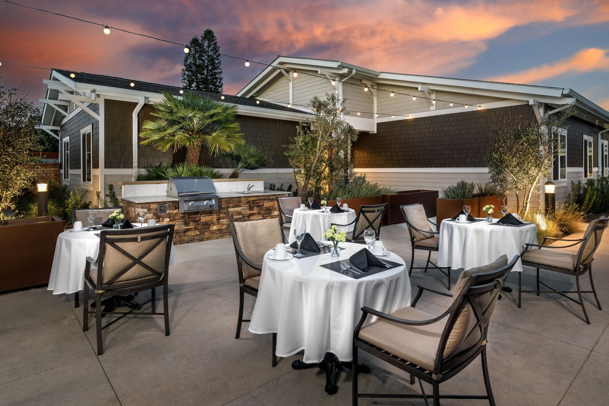 An elegant outdoor dining area with tables set under a vibrant sunset sky.