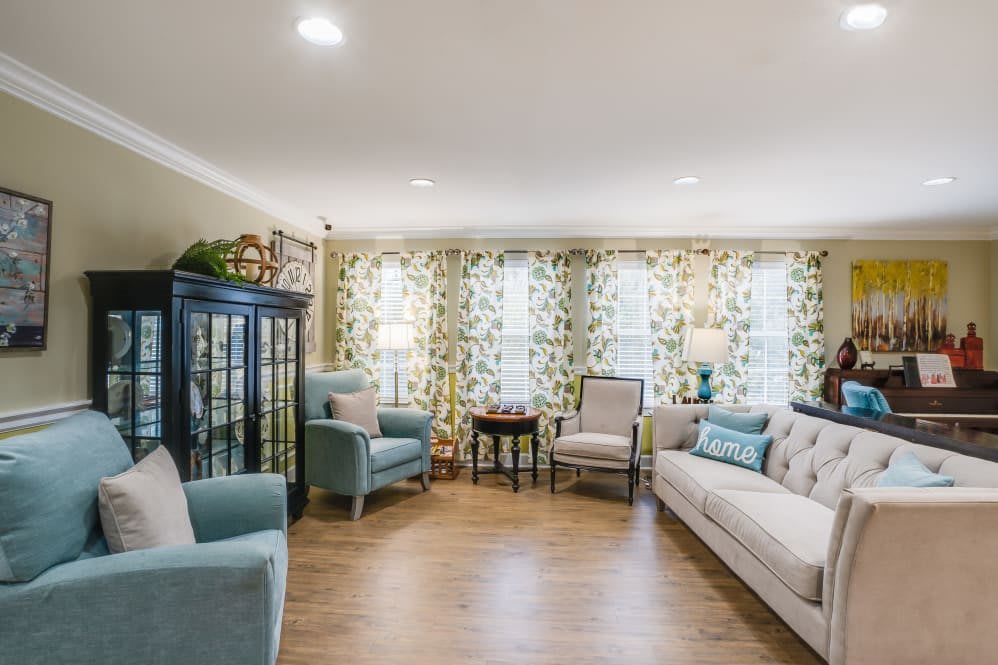 A cozy living room with armchairs, a sofa, and floral patterned curtains.