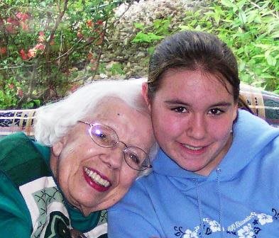 A happy moment shared between an elderly woman and a young girl outdoors.