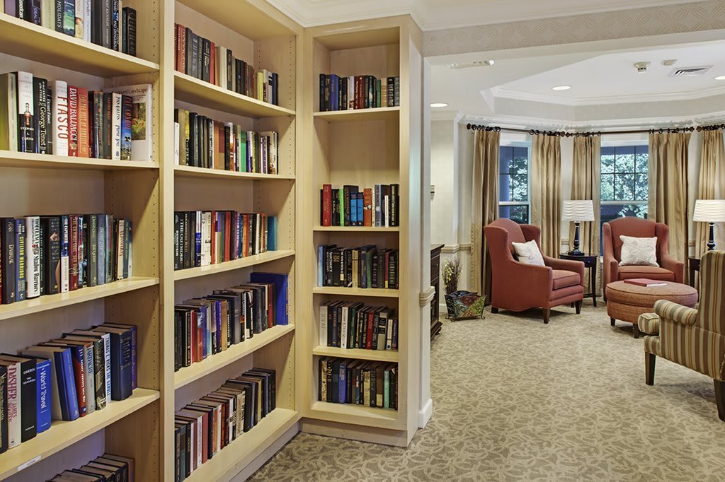 A cozy reading room with a large bookshelf and comfortable armchair.