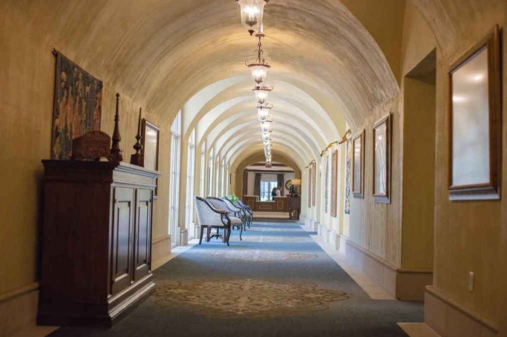 An elegant hallway with arched ceilings and vintage lighting.