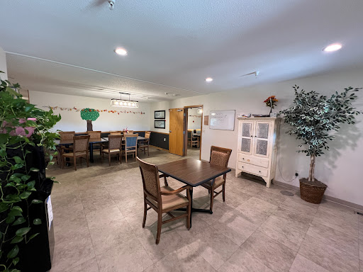 A spacious dining area featuring a wooden table with chairs, complemented by decorative plants and a welcoming atmosphere.