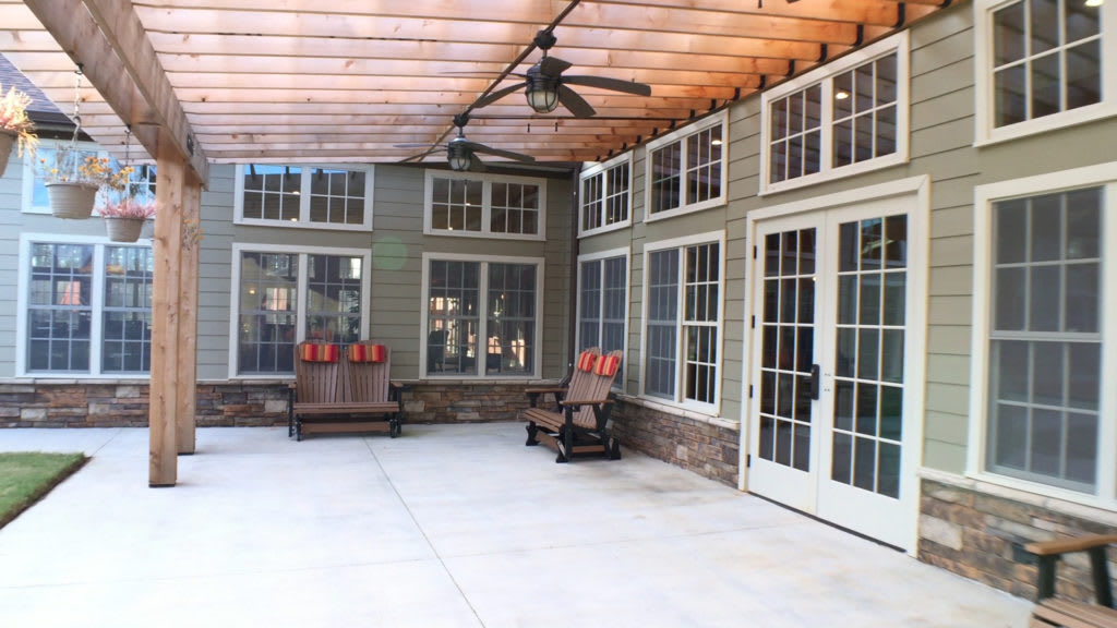 A covered patio with seating and large windows.