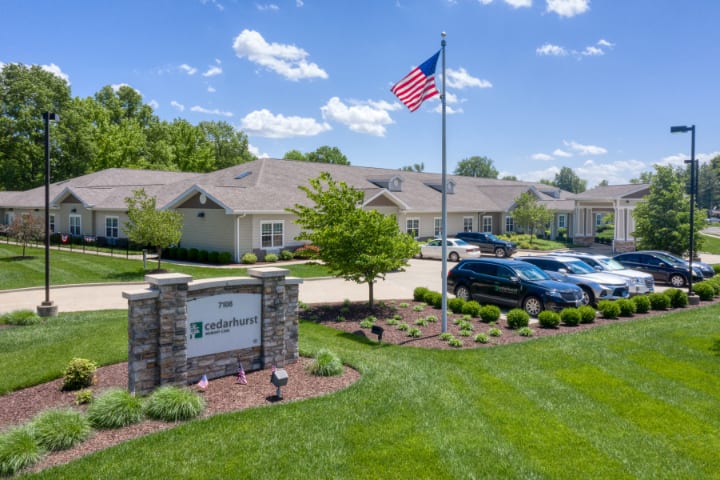A suburban building with a flagpole and parked cars under a clear blue sky.