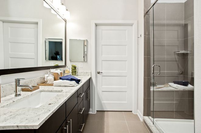 Modern bathroom with a sleek design featuring a double vanity, large mirror, and glass-enclosed shower.