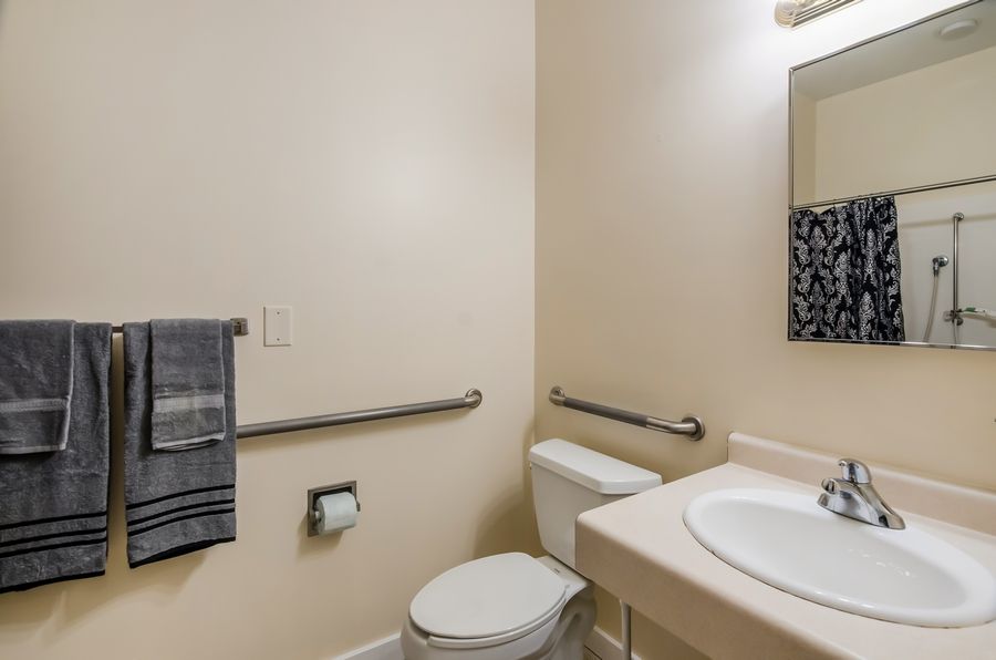 A clean and simple bathroom with accessibility features, including handrails and a towel rack.