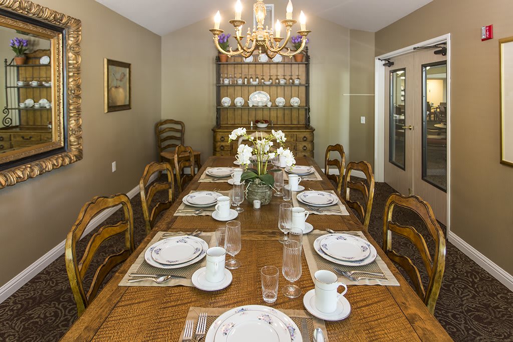 A formal dining room with an elegantly set table and a chandelier overhead.